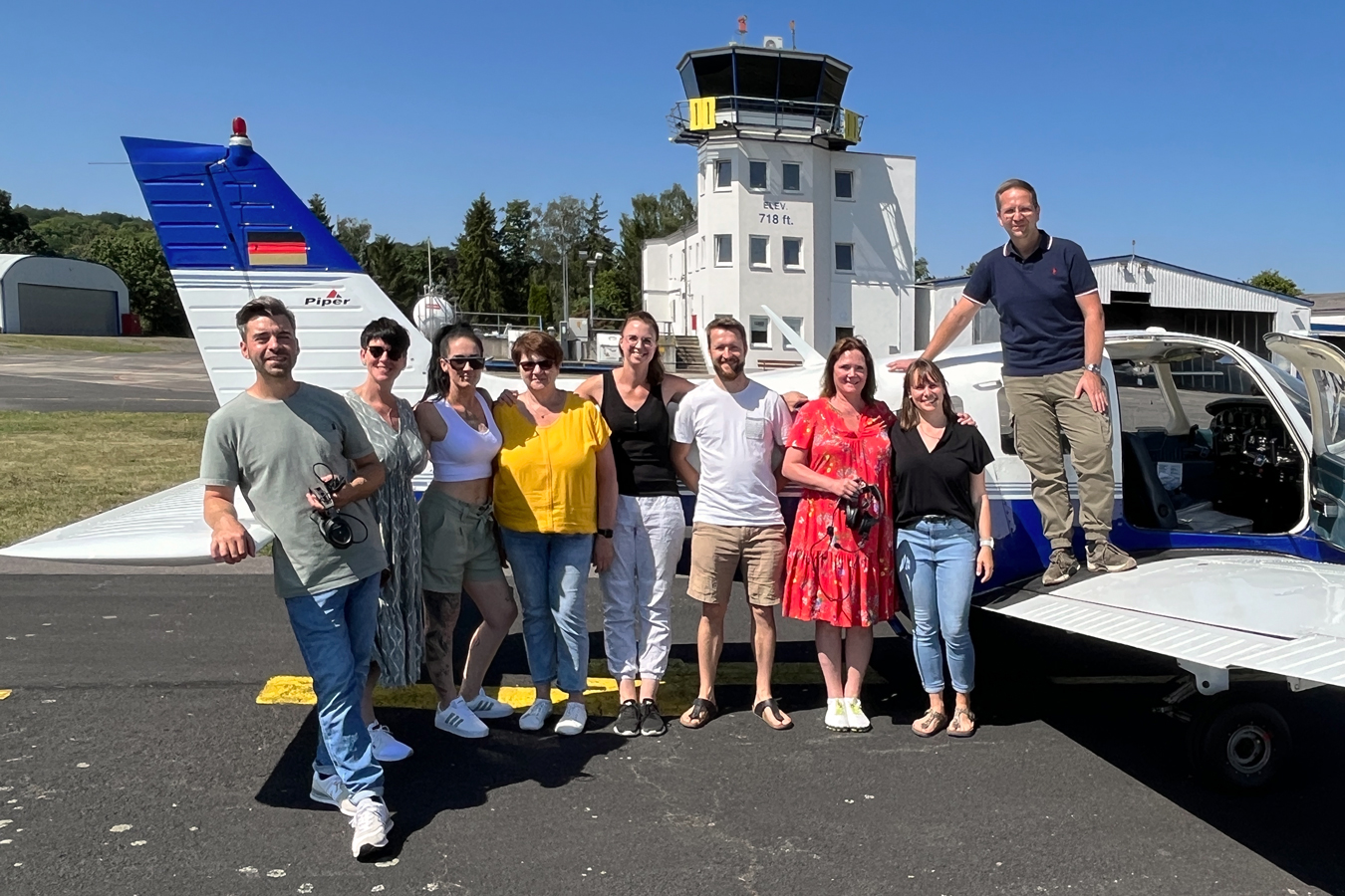 Team des NeuroZentrums steht für ein Teambild vor einem Flugzeug auf einem Flugplatz